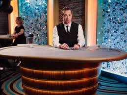 Studio kasino langsung dengan dealer profesional yang sedang memimpin permainan baccarat secara live streaming